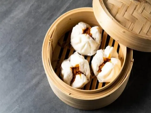 T-Pot&BBQ-Asian-Fusion-Restaurant-BBQ-Bao-College-Park Three fluffy steamed buns filled with barbecued pork, served in a bamboo steamer.